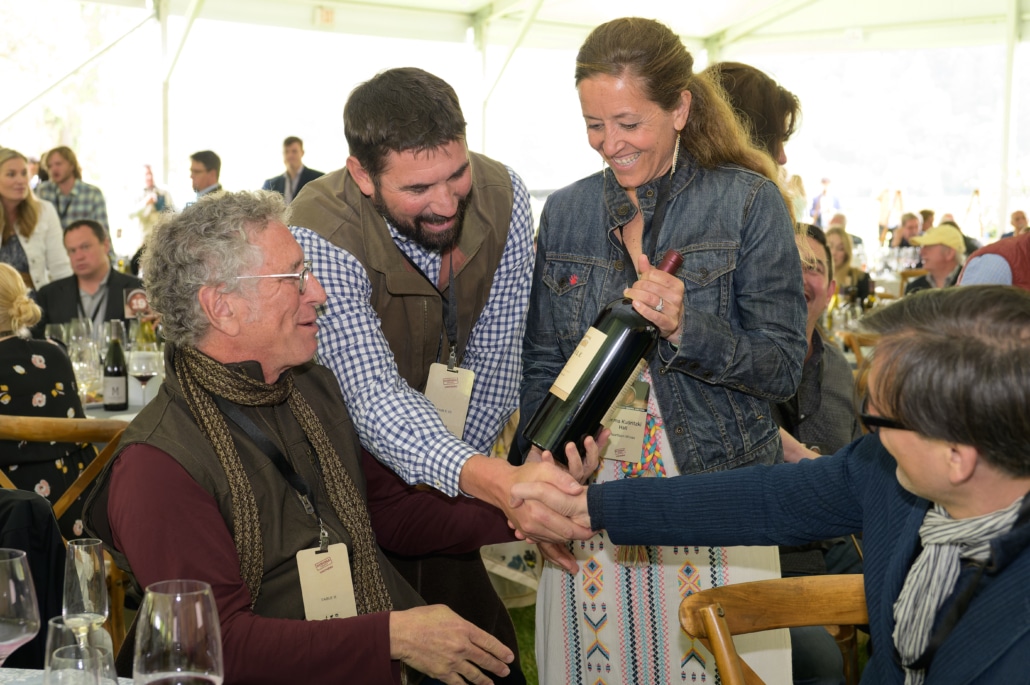 Two men an a woman looking at a bottle of red wine at Sonoma County Barrel Auction